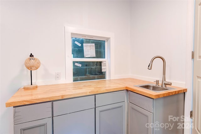 kitchen featuring gray cabinets, butcher block countertops, and sink