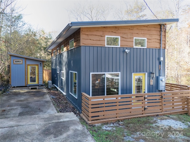 rear view of property featuring a storage unit and central AC