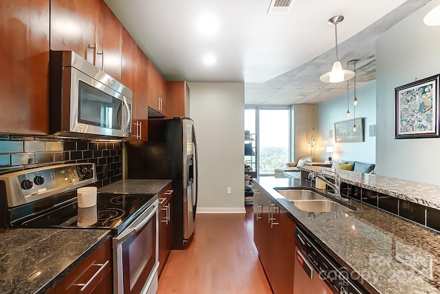 kitchen featuring stainless steel appliances, backsplash, dark hardwood / wood-style floors, pendant lighting, and sink