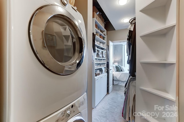 clothes washing area featuring light colored carpet and stacked washer / dryer