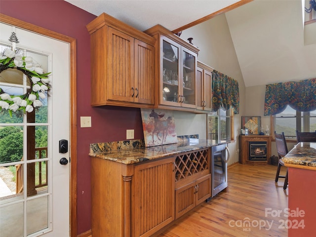 kitchen with dark stone countertops, wine cooler, light hardwood / wood-style flooring, and vaulted ceiling