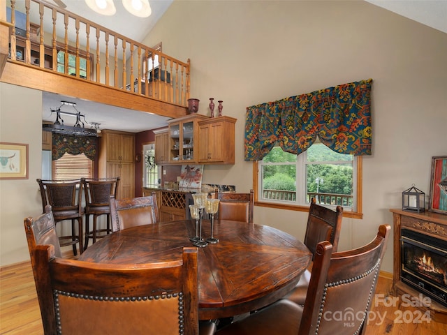 dining area with light wood-type flooring and high vaulted ceiling