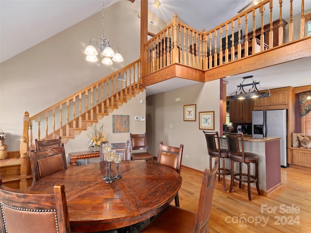 dining area featuring light hardwood / wood-style floors, a high ceiling, and a notable chandelier