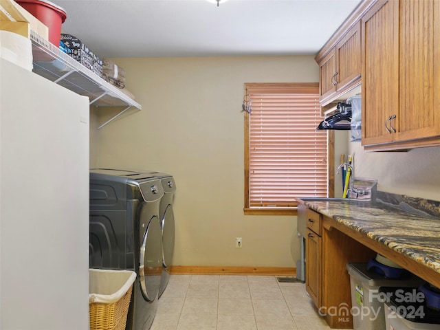 clothes washing area with light tile patterned flooring, cabinets, and separate washer and dryer