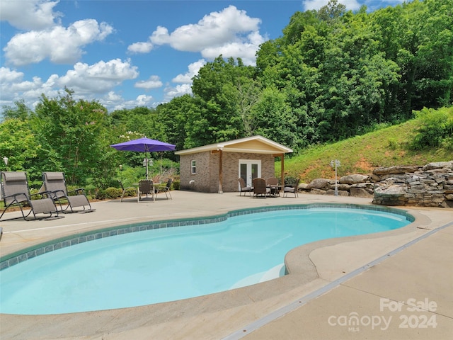 view of pool featuring an outbuilding and a patio