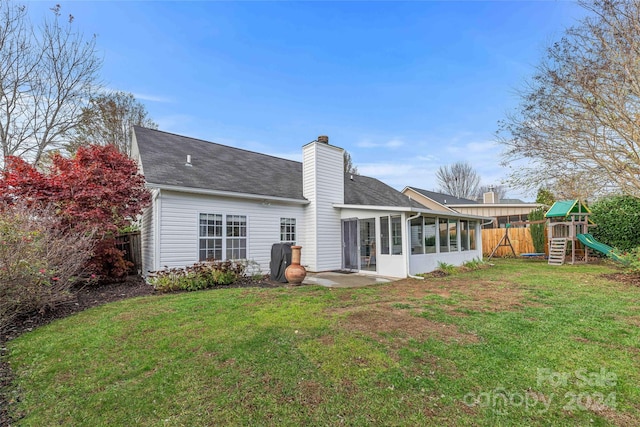 back of property featuring a playground, a sunroom, and a yard