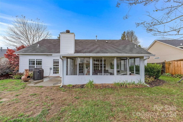 rear view of property featuring a patio, a lawn, and a sunroom