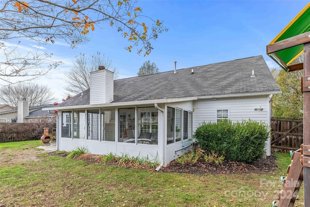 back of property with a sunroom and a lawn