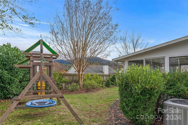 view of yard with a sunroom, a mountain view, a playground, and central AC