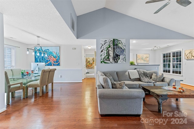 living room featuring ceiling fan, high vaulted ceiling, a textured ceiling, and hardwood / wood-style flooring