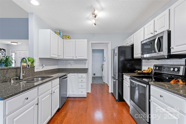 kitchen featuring dark wood-type flooring, sink, a textured ceiling, white cabinetry, and stainless steel appliances