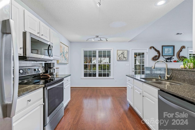 kitchen featuring dark wood-type flooring, dark stone counters, white cabinets, sink, and stainless steel appliances