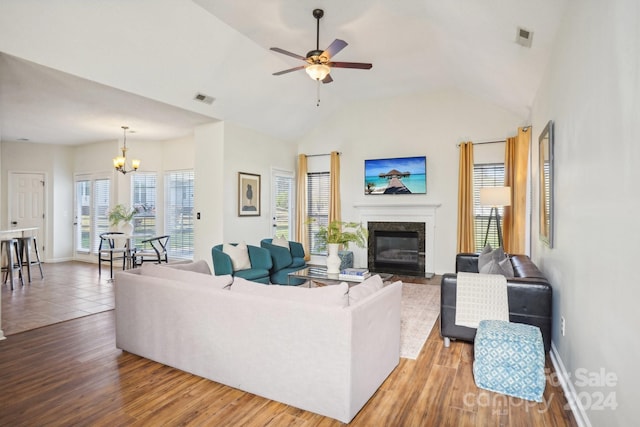 living room with hardwood / wood-style floors, ceiling fan with notable chandelier, and vaulted ceiling