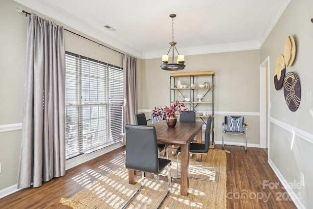 dining space featuring dark hardwood / wood-style flooring, a notable chandelier, a healthy amount of sunlight, and crown molding