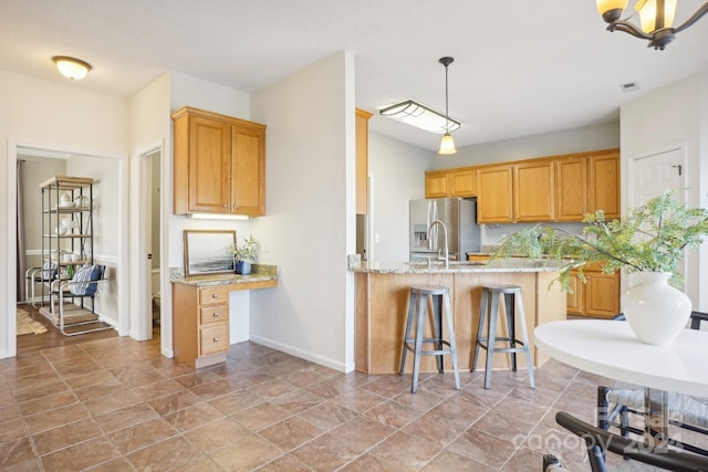 kitchen featuring light stone counters, kitchen peninsula, stainless steel refrigerator with ice dispenser, a kitchen bar, and hanging light fixtures