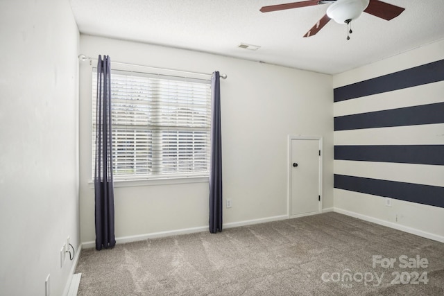 carpeted spare room featuring a textured ceiling and ceiling fan