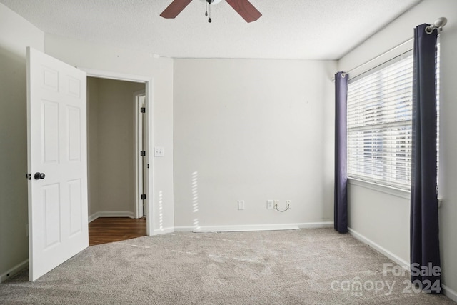 carpeted spare room featuring a textured ceiling and ceiling fan