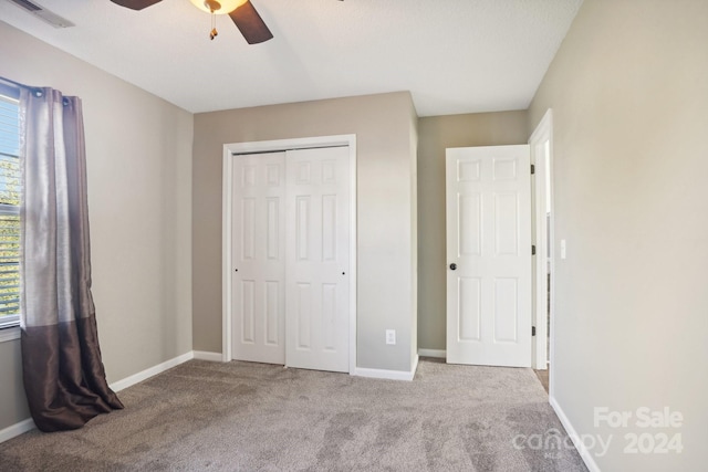 unfurnished bedroom featuring light carpet, ceiling fan, and a closet