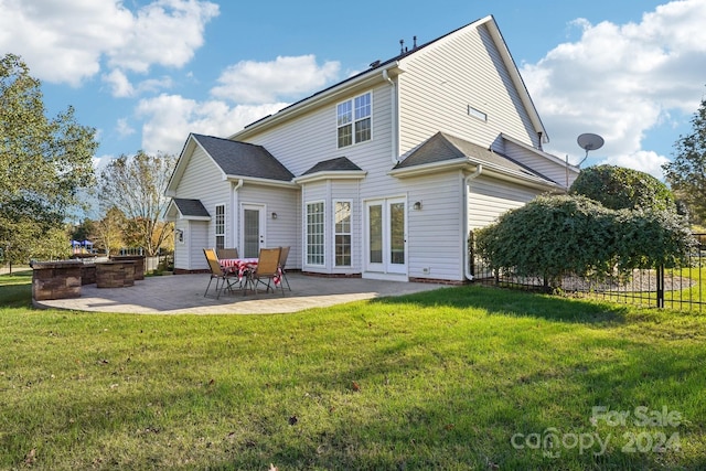 back of property with a lawn and a patio