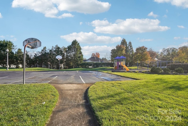 view of basketball court with a playground and a lawn