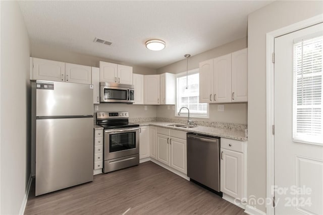 714 Knots Lndg, Clover, SC 29710 - kitchen with stainless steel appliances, a sink, white cabinetry, light stone countertops, and wood finished floors