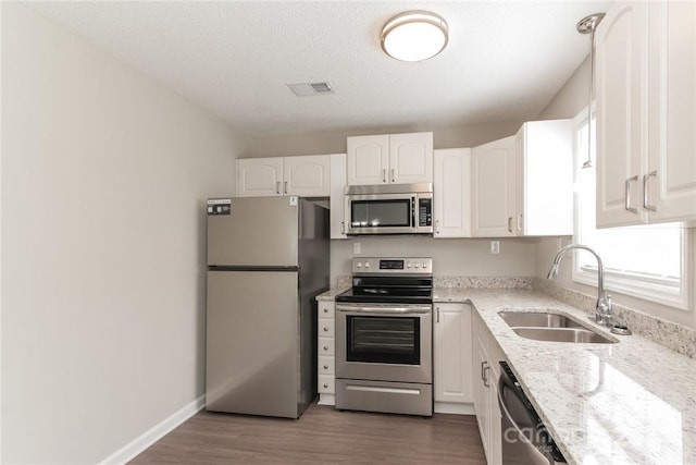 714 Knots Lndg, Clover, SC 29710 - kitchen featuring stainless steel appliances, a sink, white cabinets, wood finished floors, and light stone countertops