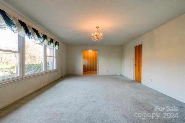 carpeted empty room featuring a chandelier