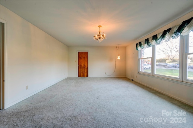 carpeted spare room with a notable chandelier