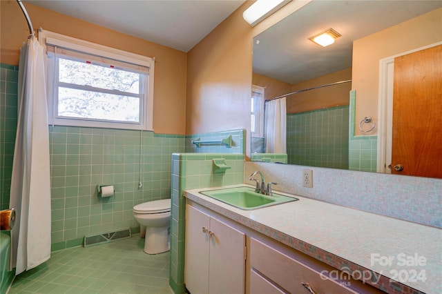 full bathroom with shower / bathtub combination with curtain, tile patterned flooring, toilet, vanity, and tile walls