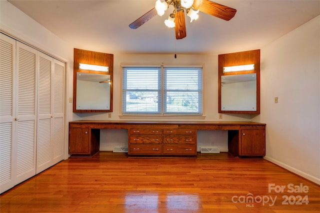 unfurnished bedroom featuring ceiling fan, a closet, built in desk, and light wood-type flooring