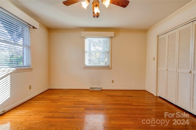 unfurnished bedroom featuring crown molding, ceiling fan, a closet, and light hardwood / wood-style floors