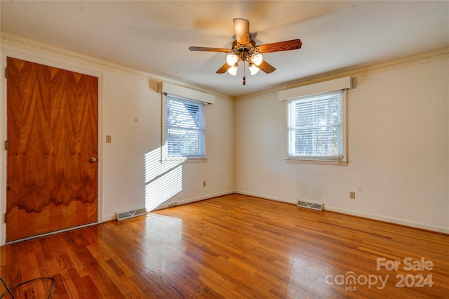 empty room with ceiling fan, hardwood / wood-style flooring, and crown molding