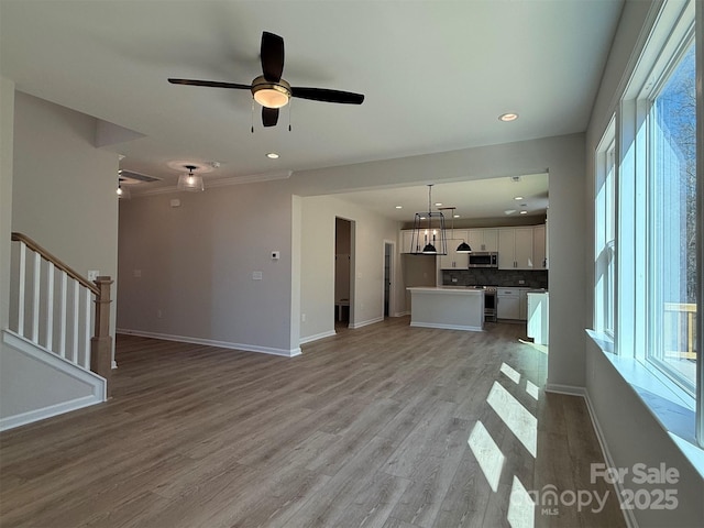 unfurnished living room with light wood-style floors, baseboards, stairway, and recessed lighting