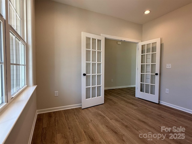 empty room with recessed lighting, french doors, baseboards, and wood finished floors