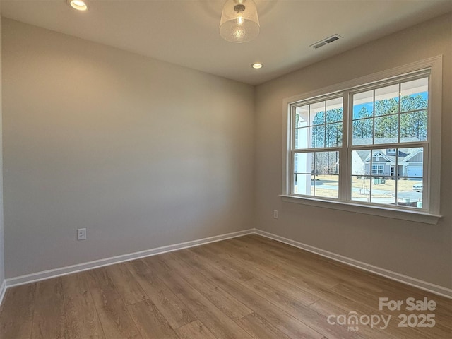 unfurnished room with visible vents, baseboards, and wood finished floors