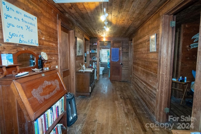 hallway featuring wooden walls, wood ceiling, and dark hardwood / wood-style flooring