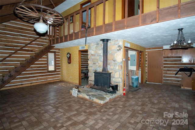 unfurnished living room with an inviting chandelier and a wood stove