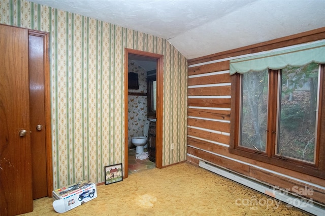 hall with a baseboard heating unit, carpet, and lofted ceiling