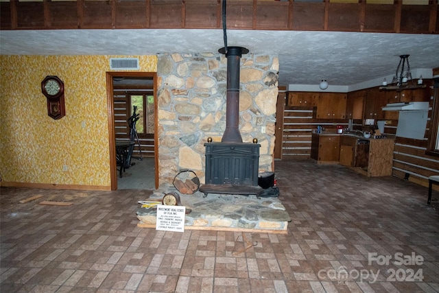 unfurnished living room featuring a wood stove and a textured ceiling