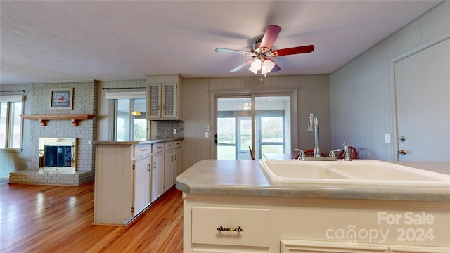 kitchen featuring light wood-type flooring, a fireplace, a healthy amount of sunlight, and sink