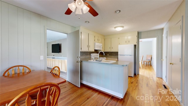 kitchen featuring white appliances, decorative backsplash, kitchen peninsula, ceiling fan, and light hardwood / wood-style flooring