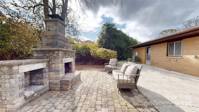 view of patio featuring central AC unit and an outdoor stone fireplace