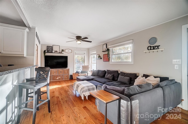 living room featuring ornamental molding, light wood-type flooring, and ceiling fan