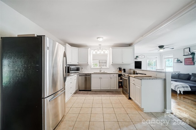 kitchen featuring white cabinets, kitchen peninsula, sink, ceiling fan, and appliances with stainless steel finishes