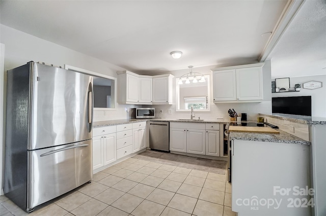 kitchen with white cabinets, sink, light tile patterned floors, appliances with stainless steel finishes, and decorative light fixtures