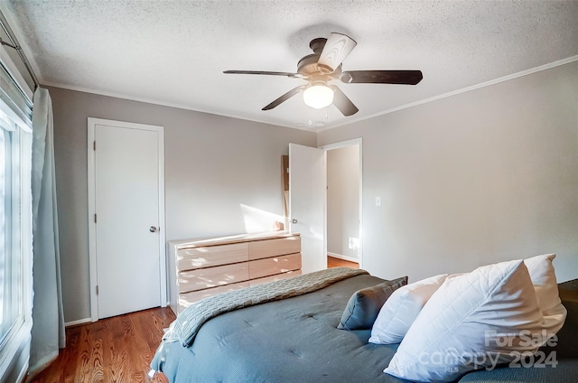 bedroom featuring hardwood / wood-style floors, ceiling fan, a textured ceiling, and ornamental molding