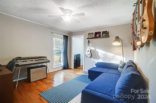 living room featuring ornamental molding, wood-type flooring, ceiling fan, and a textured ceiling