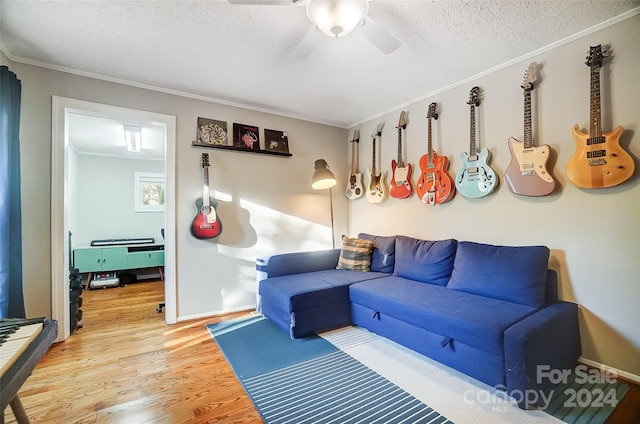 living room featuring ornamental molding, wood-type flooring, ceiling fan, and a textured ceiling