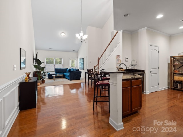 kitchen featuring light wood-type flooring, sink, hanging light fixtures, a breakfast bar area, and an island with sink