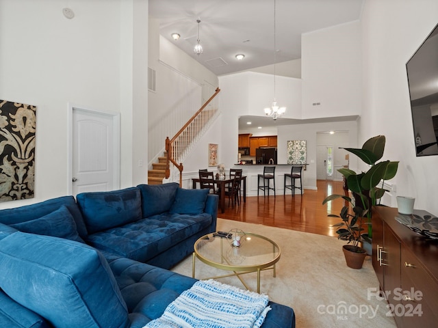 living room featuring a notable chandelier, wood-type flooring, and a towering ceiling